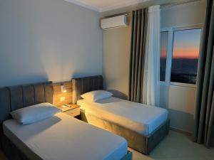 a hotel room with two beds and a window at Apartments Vila Ardi in Sarandë