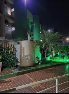 a building with a fence and palm trees at night at Hotel Paranoá in Jabuticabal