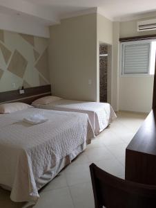 a bedroom with two beds and a window at Hotel Paranoá in Jabuticabal