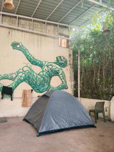 a black tent in front of a wall with a painting at Art Bliss Rishikesh - Yoga Hostel & Café in Rishīkesh