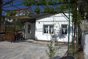 a patio with a white house with a table at Little Vine House in Mostar
