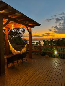 a hammock on a deck with a sunset in the background at Morada Sunset in Imaruí
