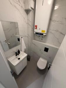 a white bathroom with a toilet and a sink at Apartman Royal in Posušje