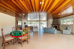 a living room with a wooden ceiling and a table and chairs at Pousada Sol da Mantiqueira in Campos do Jordão