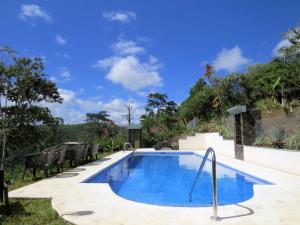 a swimming pool with chairs and a blue sky at Rinconcito Verde in Ujarrás