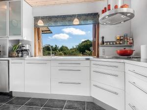 a kitchen with white cabinets and a large window at 6 person holiday home in Borre in Borre +5 photos