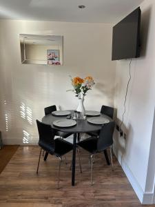 a dining room table with chairs and a vase with flowers at Comfort Horizon Egham in Egham