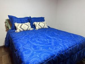 a bed with a blue comforter and two pillows at El Regreso in Chuí