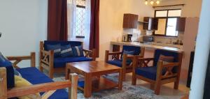 a living room with a table and chairs and a kitchen at TajiS Diani Chic 1 BR with swimming pool in Diani Beach