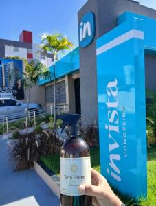 a person holding a bottle of alcohol in front of a sign at pousada mar livre in Aracaju