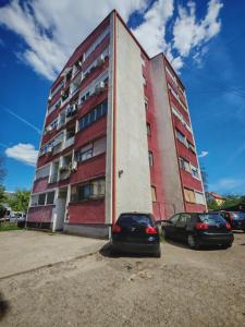 a building with two cars parked in front of it at Apartman ANA in Pirot