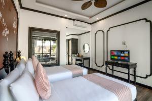 two beds in a room with a mirror and a television at Luang Prabang Vang Luang Hotel in Luang Prabang
