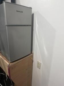 a white refrigerator freezer sitting next to a wooden box at stayhouse in Gapan