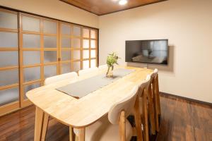 a dining room with a wooden table and a tv at Staylinks Nara Kitamachi in Nara