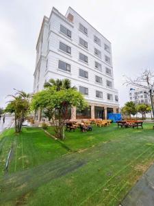 a large white building with picnic tables in front of it at Khách Sạn Thăng Long 2 in Sầm Sơn