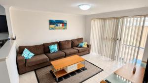 a living room with a brown couch and a table at Escape to 39 at Cape View in Busselton