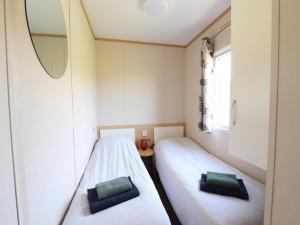 two beds in a small room with a mirror at Cozy chalet with a view over the fields in Drachten