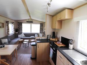 a small kitchen and living room with a couch at Cozy chalet with a view over the fields in Drachten