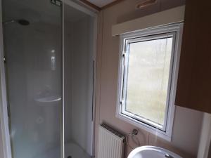 a bathroom with a shower and a sink and a window at Cozy chalet with a view over the fields in Drachten