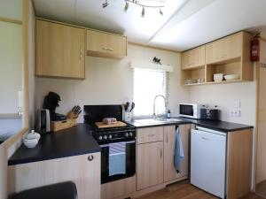 a kitchen with wooden cabinets and a black counter top at Cozy chalet with a view over the fields in Drachten +19 photos