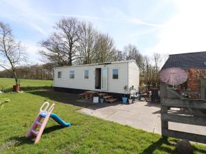 a small white tiny house in a yard at Cozy chalet with a view over the fields in Drachten