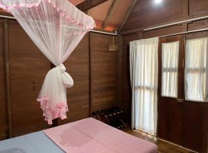 a bedroom with a bed with a mosquito net at Cool Banyan Cabana in Trincomalee