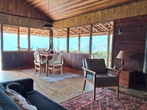 a living room with a table and chairs and windows at Cabana do Sol -São Francisco Xavier in São José dos Campos