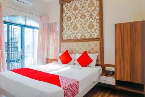 a bedroom with a bed with red pillows and a window at Hotel O Rest Inn in Yeraoda +28 photos
