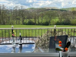 a table with two glasses and a bottle of wine on a balcony at Tilly Cottage - overlooking Pendle Hill in Barrowford