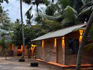 a small wooden cabin with palm trees in the background at Coconut Beach in Bentota