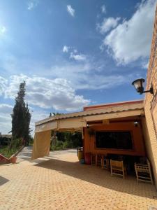 a building with awning with tables and chairs in it at Route Agafay in Aït Ali