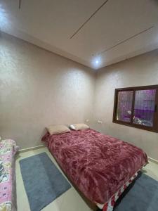 a bedroom with a bed with a purple comforter at Route Agafay in Aït Ali