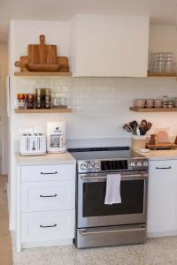 a kitchen with a stove and white cabinets at Cottage Three - Hidden Gem on Hanalei River in Hanalei