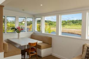 a room with a table and a chair and windows at Cottage Three - Hidden Gem on Hanalei River in Hanalei