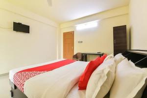 a bedroom with a bed with red and white pillows at Hotel O VR Lodge in Pathanāmthitta