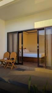 a bedroom with a bed and two chairs in a room at Swarga Rinjani in Sembalun Lawang