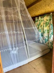 a bed with a net on top of it at Martins Ocam-Ocam Cottages in New Busuanga