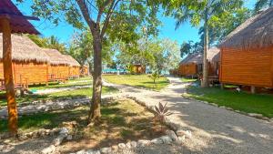 a group of buildings with straw roofs and trees at Paradise Beach Bacalar A Pie De Laguna in Bacalar