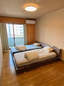 a bedroom with two beds and a window at Guest House KURA 776 Mt Fuji View and 1 min to Gekkoji Station in Fujiyoshida