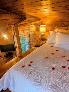 a bedroom with a white bed with red roses on it at Owl's Perch Treehouse in Sooke