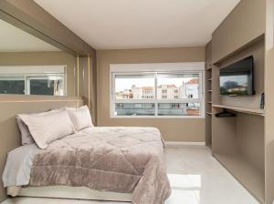a bedroom with a bed and a tv and two windows at Studio 208 Premium 450m do Consulado EUA in Porto Alegre +23 photos