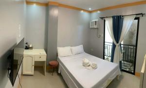 a small room with a bed and a desk and a window at ANDABAY Tourist Inn in Anda +21 photos