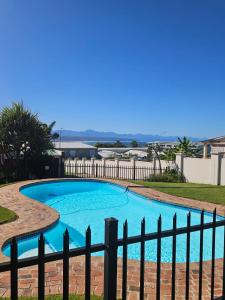 a large blue swimming pool next to a fence at Marine View in Plettenberg Bay