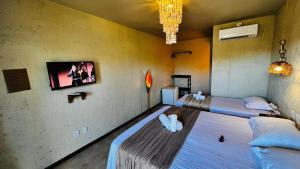 two beds in a room with a tv on the wall at Pousada Ybitu in São Miguel do Gostoso