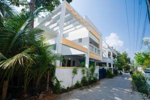 a white building on a street with a palm tree at Classic Horizon in Mahabalipuram