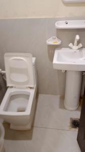 a white bathroom with a toilet and a sink at Hotel Seven View Lahore in Lahore