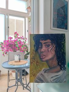 a painting of a woman next to a table with flowers at Four Palms Guest House in Praia