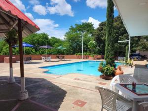 a swimming pool with chairs and tables and umbrellas at Hotel OK El Edén in Tocaima