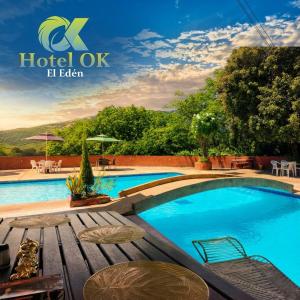 a pool at a hotel with tables and chairs at Hotel OK El Edén in Tocaima