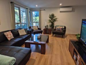 a living room with couches and a flat screen tv at Grey Gum Getaway Tecoma in Belgrave